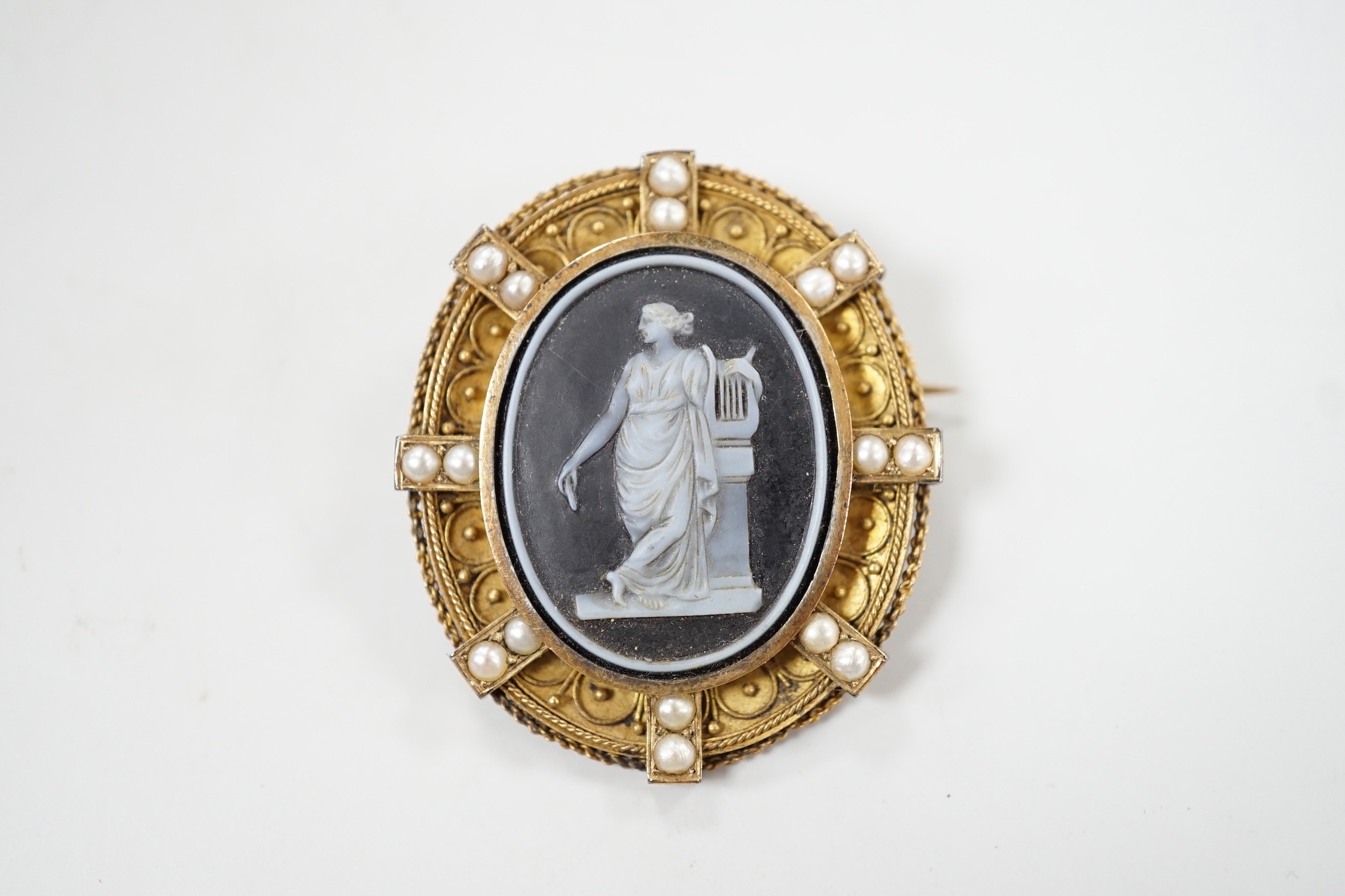 A Victorian canettile work yellow metal and sardonyx? cameo and split pearl set oval brooch, carved with Erato, 38mm, gross weight 8.5 grams.